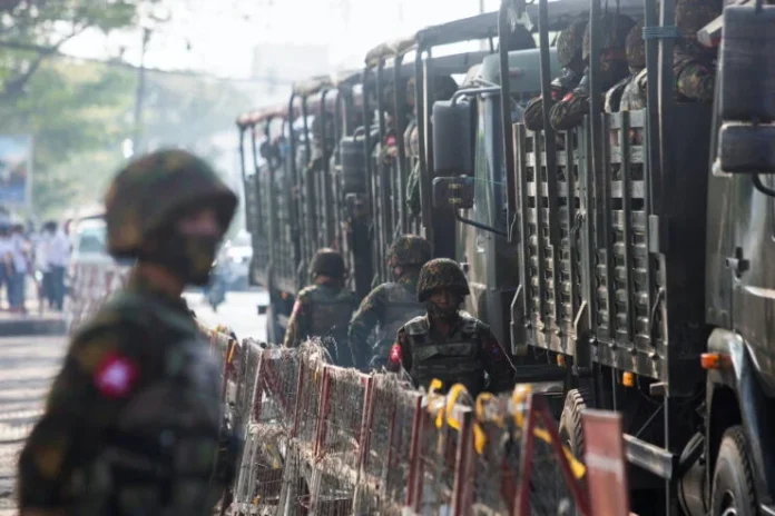 Soldiers-stand-next-to-military-vehicles-as-people-gather-to-protest-against-the-military-coup-in-Yangon-e1639406800986