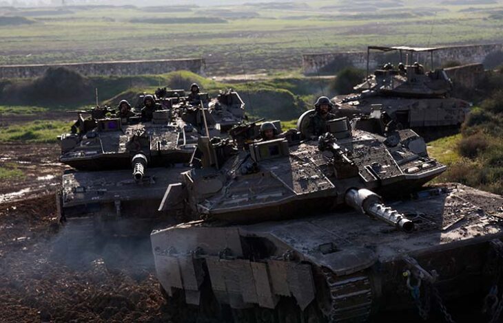 Israeli soldiers ride tanks while moving out of the Gaza Strip, as seen from southern Israel