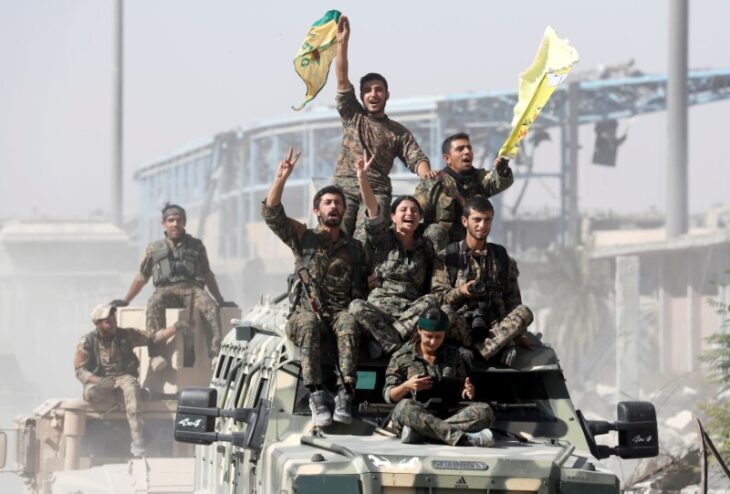 FILE PHOTO: Kurdish-led militiamen ride atop military vehicles as they celebrate victory over Islamic State in Raqqa